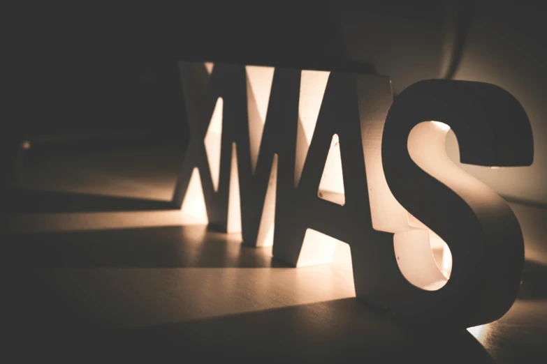 a couple of letters sitting on top of a table, by Matija Jama, pexels contest winner, complex lights, christmas, warm lighting with cool shadows, 15081959 21121991 01012000 4k