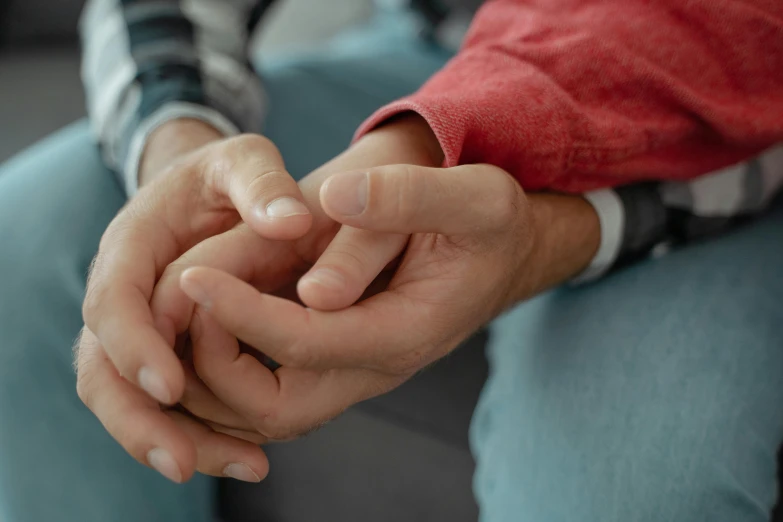 a close up of a person holding a persons hand, two men hugging, sitting on a couch, lightly dressed, mental health