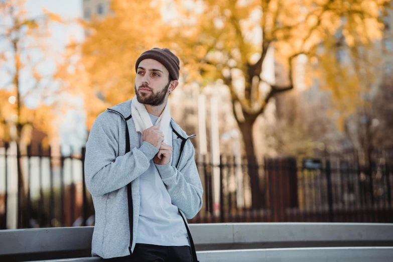 a man sitting on a bench in a park, a portrait, inspired by Raphaël Collin, pexels contest winner, he also wears a grey beanie, standing in a city street, avatar image, fall season