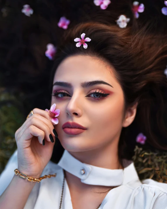 a woman laying in the grass with flowers in her hair, a colorized photo, inspired by Maryam Hashemi, trending on pexels, thick fancy makeup, beautiful arab woman, lgbtq, sexy lips :5 stylish