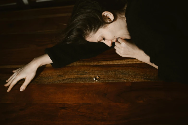 a woman laying on top of a wooden floor, by Elsa Bleda, trending on pexels, visual art, heartbroken, on a table, shy looking down, 15081959 21121991 01012000 4k