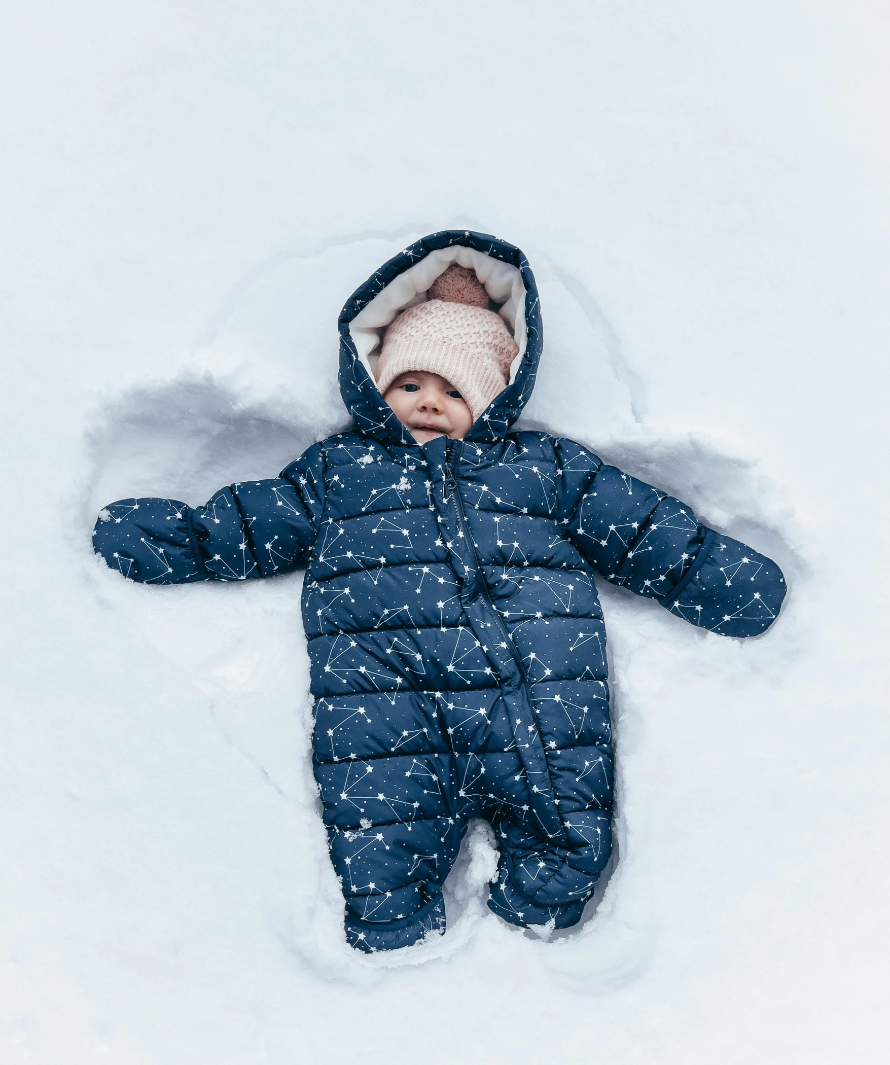 a baby in a snow suit laying in the snow, an album cover, inspired by Myles Birket Foster, pexels contest winner, full body shot 4k, navy, high angle shot, gif