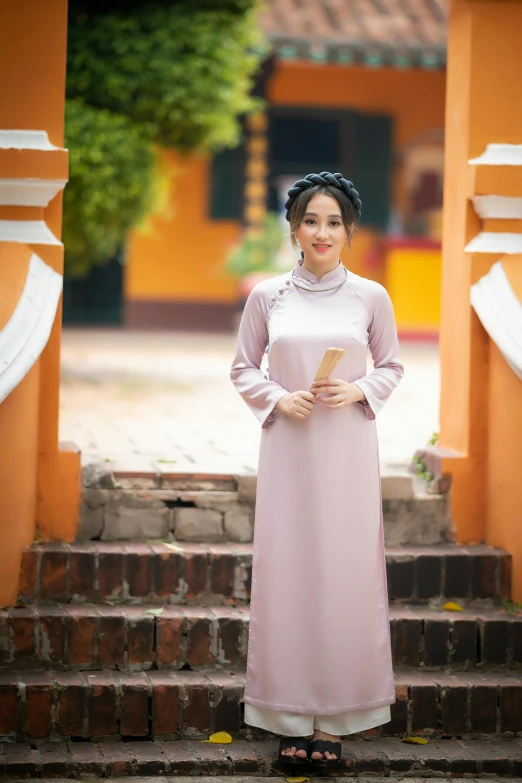 a woman in a pink dress standing on some steps, a picture, inspired by Ruth Jên, pexels contest winner, ao dai, wearing a grey robe, brown, authentic costume