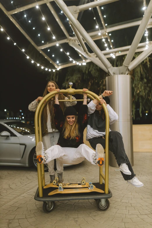 a group of people sitting on top of a cart, standing on a skateboard, during the night, dasha taran, swings