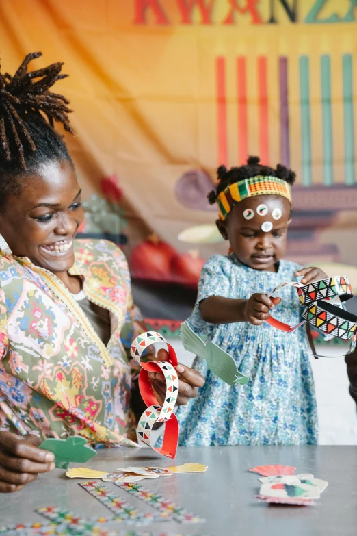 a group of people that are sitting at a table, by Arabella Rankin, pexels contest winner, black arts movement, west africa mask patterns style, children playing with pogs, wearing an african dress, toddler