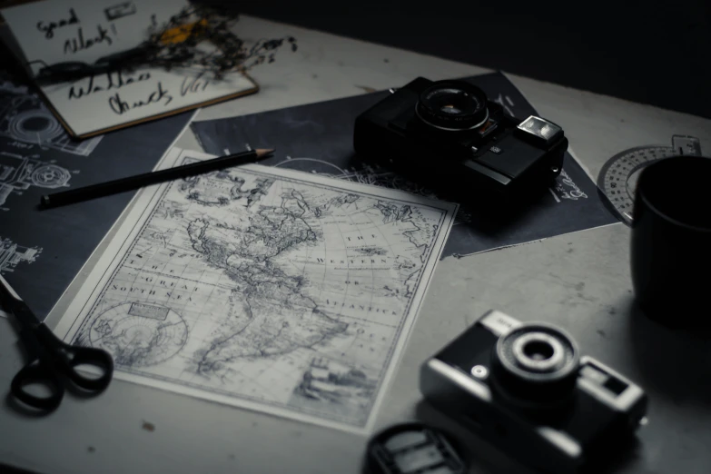a camera sitting on top of a table next to a map, a black and white photo, miscellaneous objects, medium format, the photography artwork, cartographic