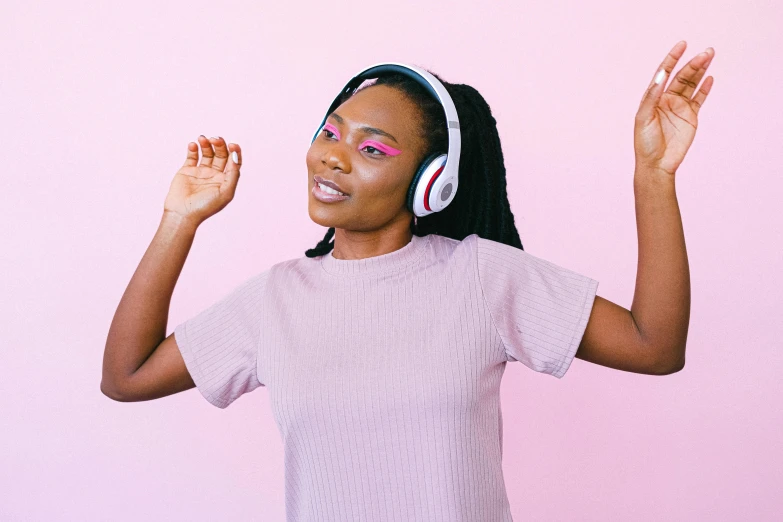 a woman wearing headphones in front of a pink wall, trending on pexels, other women dancing behind, african canadian, pokimane, with a white background