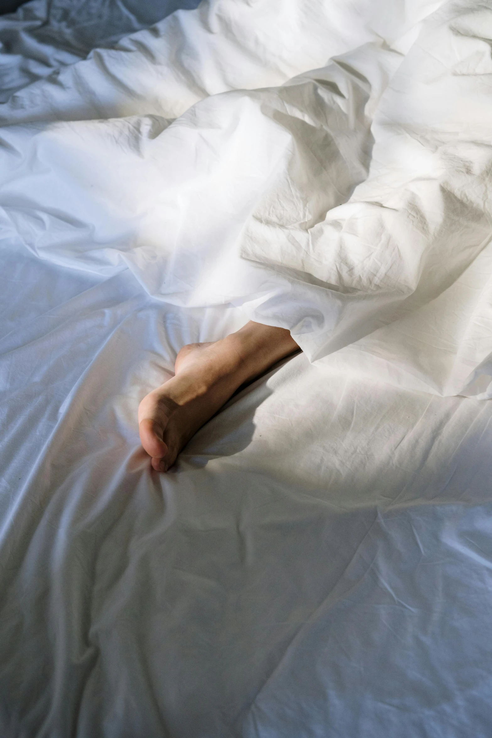 a person laying on top of a bed covered in white sheets, holding hand, stalking, slightly sunny, sunken