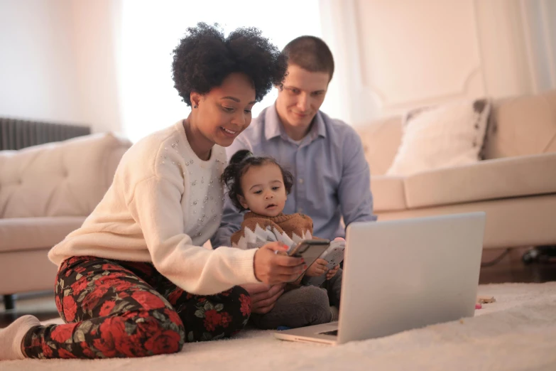 a man and woman sitting on the floor looking at a laptop, a cartoon, by Carey Morris, pexels, portrait of family of three, toddler, diverse, decoration