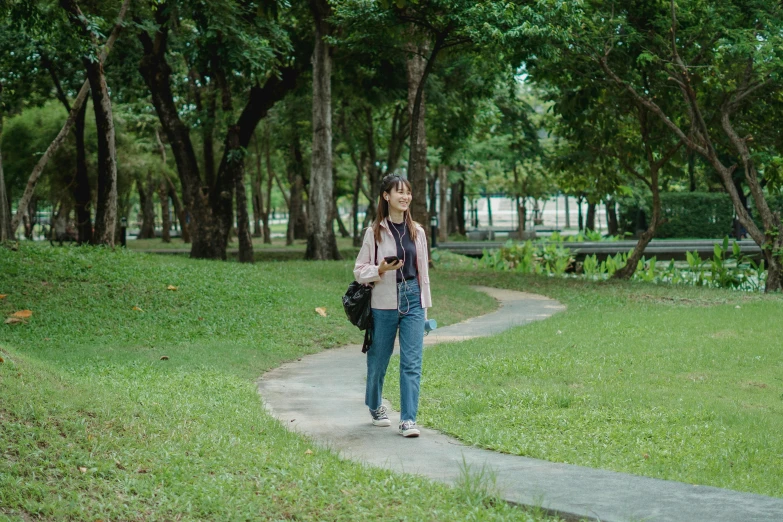 a woman walking down a path in a park, by Tan Ting-pho, pexels contest winner, happening, handsome girl, avatar image, student, still frame from a movie