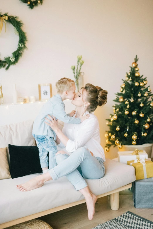 a woman and a child sitting on a couch in front of a christmas tree, pexels contest winner, romanticism, lovely kiss, avatar image, scandinavian, casually dressed