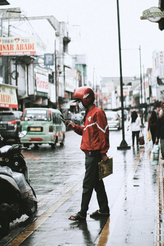 a man in a red jacket on a city street, pexels contest winner, indonesia, delivering parsel box, grey skies rain, gif