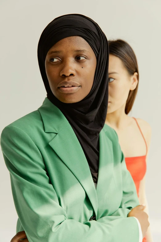 a couple of women standing next to each other, by Ellen Gallagher, hurufiyya, wearing green suit, black young woman, looking away from the camera, subject detail: wearing a suit