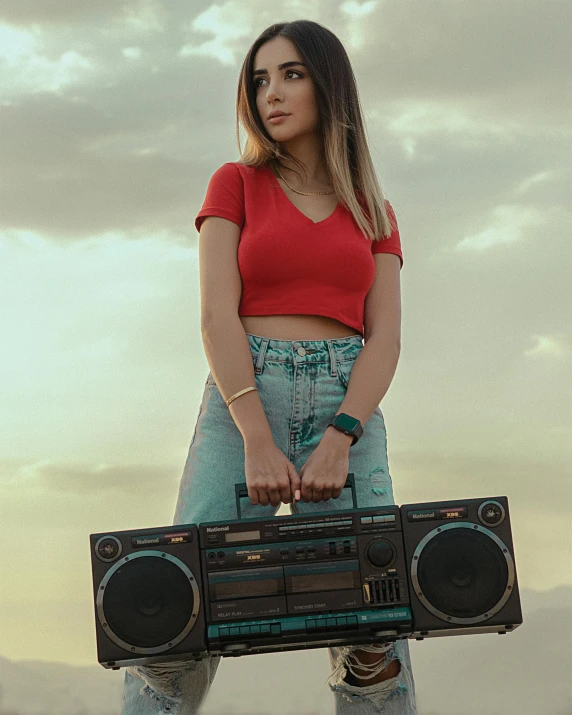 a woman in a red shirt is holding a boombox, inspired by Elsa Bleda, trending on pexels, sunset mood, wearing a crop top, portrait mode photo, promotional image
