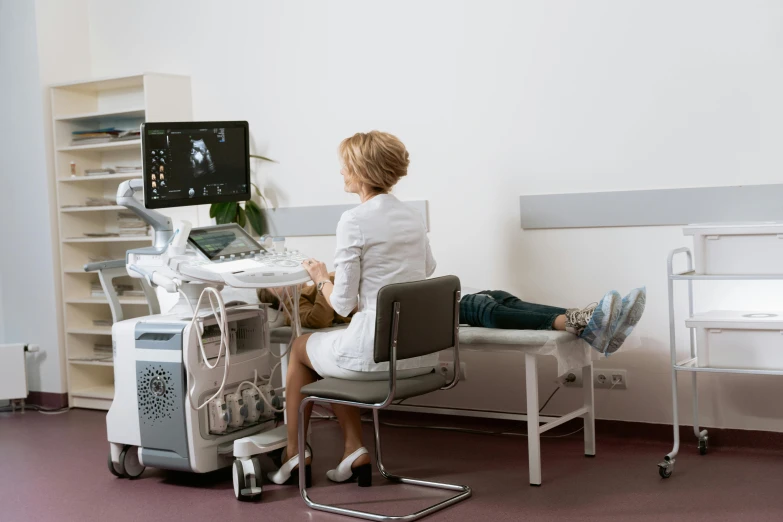 a woman sitting at a desk in front of a computer, medical equipment, grey, wētā fx, histological