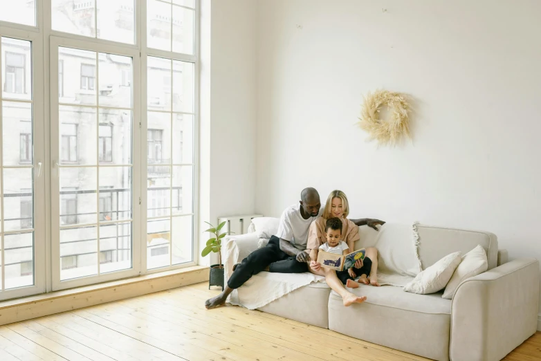 a family sitting on a couch in a living room, pexels contest winner, minimalism, city apartment cozy calm, thumbnail, cream - colored room, natural light outside