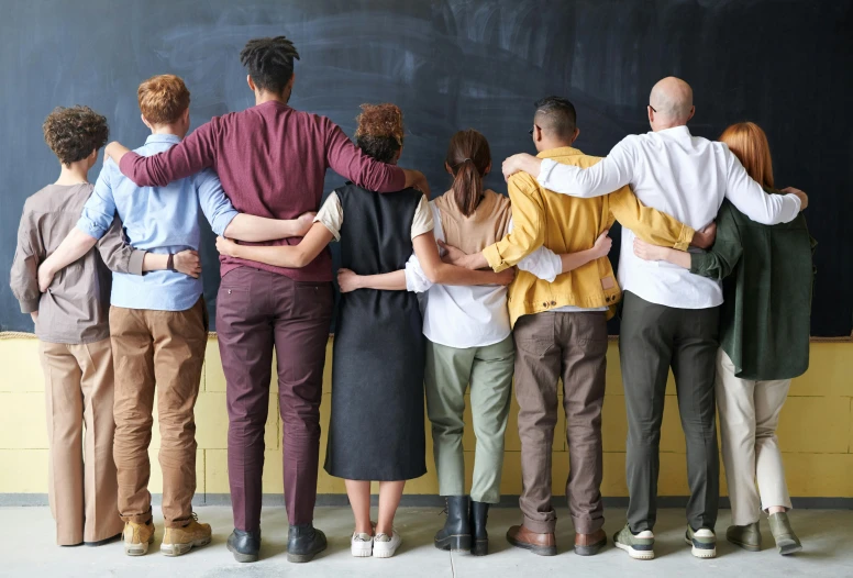 a group of people standing in front of a blackboard, by Anna Findlay, trending on pexels, hunched shoulders, colorful uniforms, hugging each other, 15081959 21121991 01012000 4k