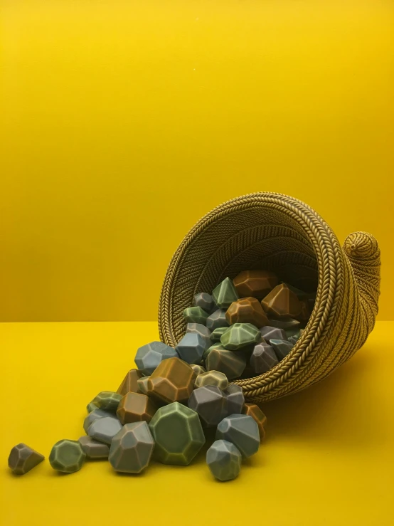 a basket filled with rocks sitting on top of a yellow surface, by Ryan Pancoast, conceptual art, 3 d metallic ceramic, multi colored, hexagonal, chocolate