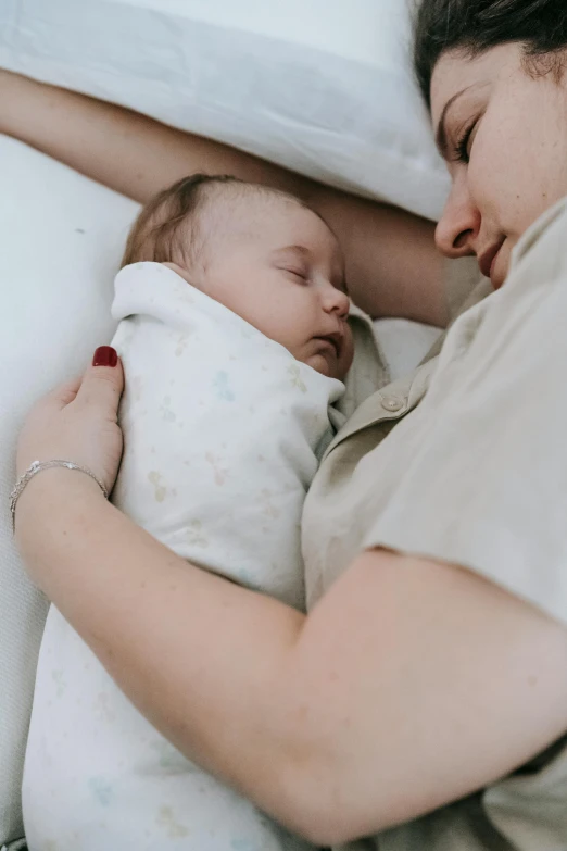 a woman holding a baby wrapped in a blanket, pexels contest winner, sleeping, with a white, 1 2 9 7, low quality photo