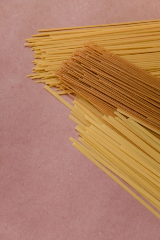 a pile of spaghetti noodles on a pink surface, by David Simpson, unsplash, highly detailed image, raw sienna, made of bamboo, various styles