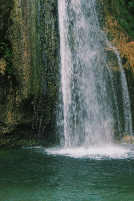 a man standing in front of a waterfall, an album cover, unsplash, renaissance, puerto rico, zoomed in, cyprus, low quality photo