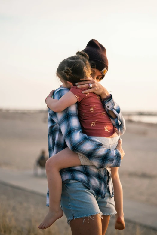 a woman carrying a child on her back at the beach, by Niko Henrichon, pexels, square, two men hugging, teenage girl, 256435456k film