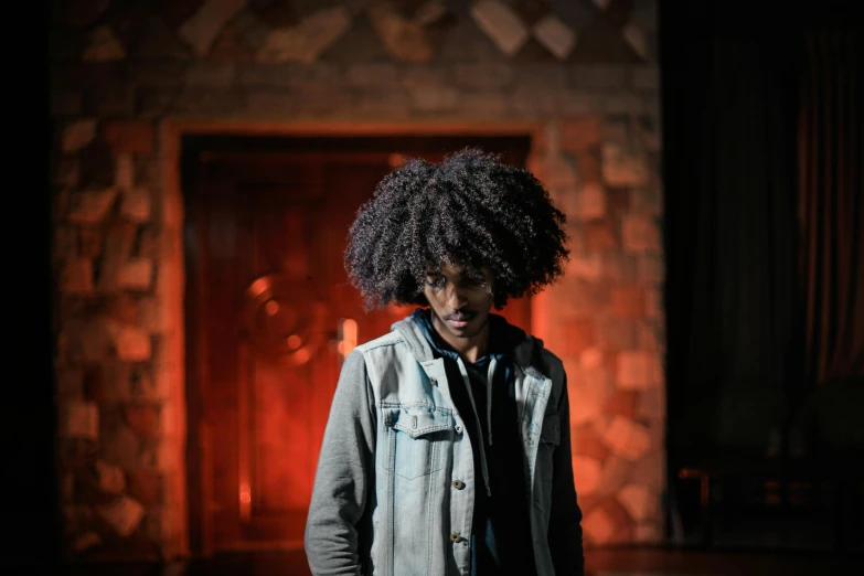 a man standing in front of a fire place, an album cover, by Afewerk Tekle, pexels contest winner, 3 actors on stage, curly afro, grimdark dramatic lighting, student