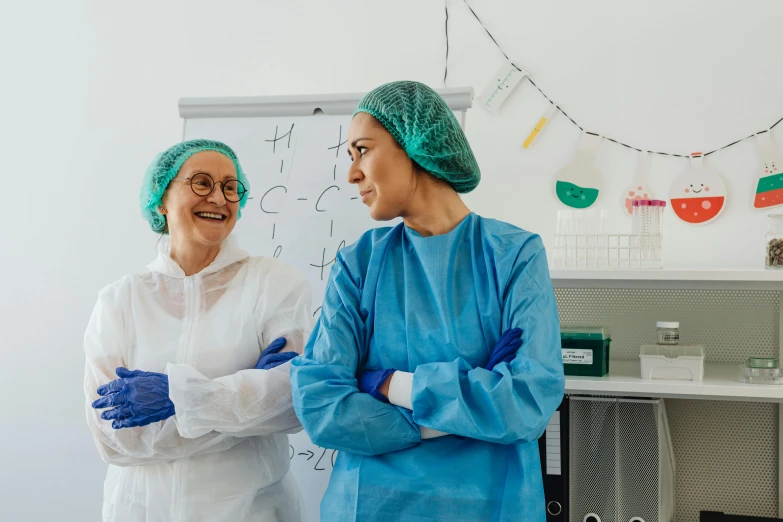 a couple of women standing next to each other, by Lee Loughridge, pexels contest winner, happening, surgical gown and scrubs on, laboratory background, amused, avatar image