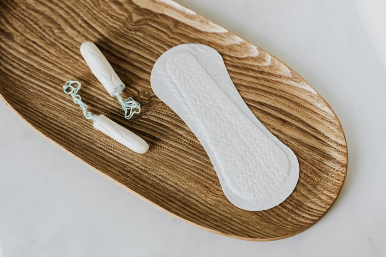 a pair of sanitary pads sitting on top of a wooden tray, inspired by Wilhelm Hammershøi, trending on pexels, female model, very elongated lines, oak, silver，ivory