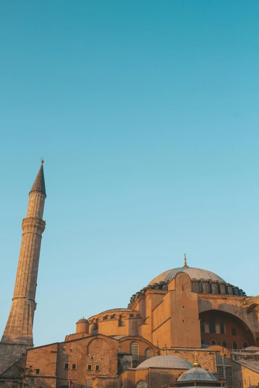 a large building with a clock tower in front of it, an album cover, inspired by Altoon Sultan, trending on unsplash, hurufiyya, byzantine ruins, sky blue, dome, soft morning light