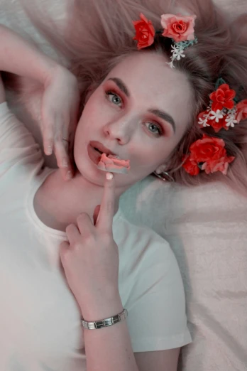 a woman laying on a bed with flowers in her hair, a colorized photo, trending on pexels, aestheticism, portrait of kim petras, eating mars bar candy, low quality video, red blush