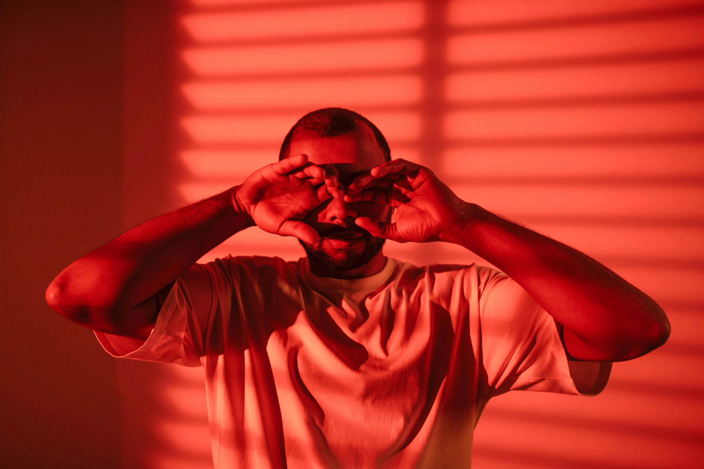 a man covering his eyes with his hands, an album cover, pexels contest winner, visual art, red orange lighting, mkbhd, light entering through a blind, demna gvasalia