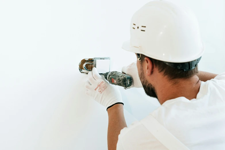 a man in a hard hat working on a wall, pexels contest winner, white bg, exposing screw, background image, instagram post