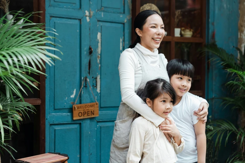 a woman and two children standing in front of a blue door, pexels contest winner, in front of ramen shop, al fresco, asian woman, ivy's