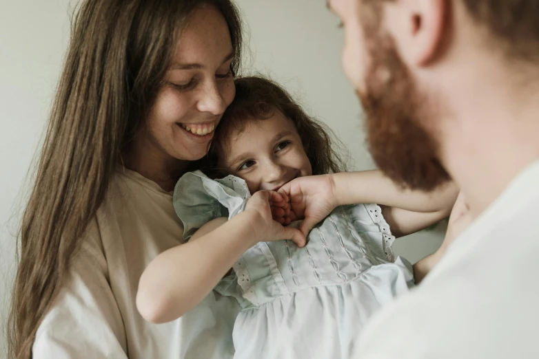 a man holding a little girl in his arms, pexels contest winner, woman holding another woman, avatar image, smiling sweetly, nursing