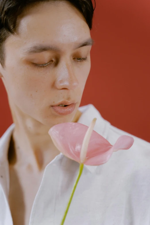 a man in a white shirt holding a pink flower, inspired by Gao Xiang, aestheticism, non binary model, with red haze, photoshoot for skincare brand, video still