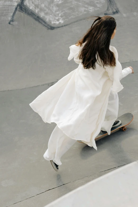 a girl in a white dress riding a skateboard, inspired by Zaha Hadid, unsplash, wearing flowing robes, wearing a linen shirt, high angle close up shot, short puffy pants made of silk