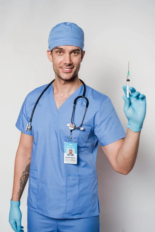 a man in scrubs holding a syet in one hand and a syet in the other, a colorized photo, shutterstock, syringe, high quality costume, attractive man, 2019 trending photo