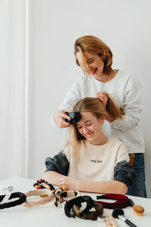 a woman blow drying another woman's hair, by Olivia Peguero, trending on pexels, renaissance, teenagers, product introduction photo