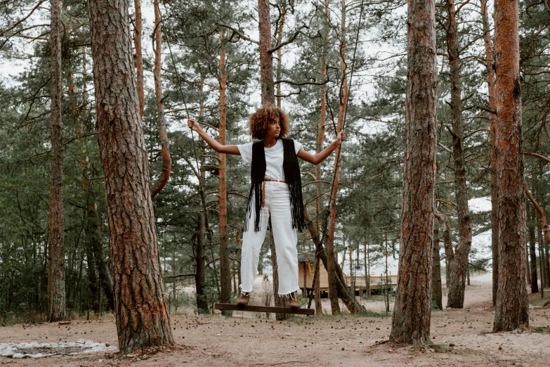 a woman standing on a swing in the woods, a photo, with afro, outfit : jeans and white vest, avatar image, fullbody photo