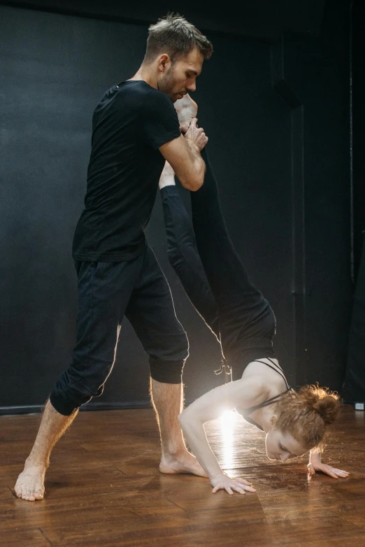 a man and a woman doing a handstand on a wooden floor, by Elizabeth Polunin, arabesque, vivid studio light, sydney hanson, an ahoge stands up on her head, fighting scene