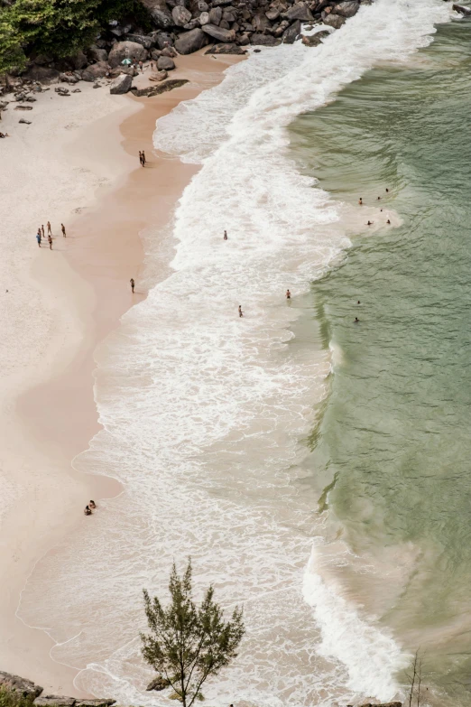 a group of people standing on top of a sandy beach, by Nina Hamnett, trending on unsplash, renaissance, helicopter view, pristine rippling oceanic waves, pink white and green, south african coast