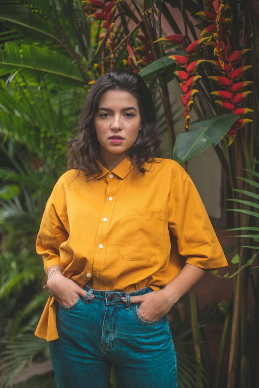 a woman wearing a yellow shirt and blue jeans, by Alejandro Obregón, pexels contest winner, renaissance, collared shirt, lorde, lush surroundings, cropped wide sleeve