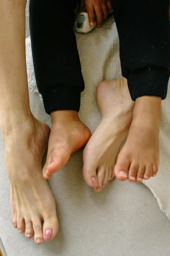 a couple of people sitting on top of a bed, by Victorine Foot, unsplash, hyperrealism, big feet, children's, japanese, smooth texture