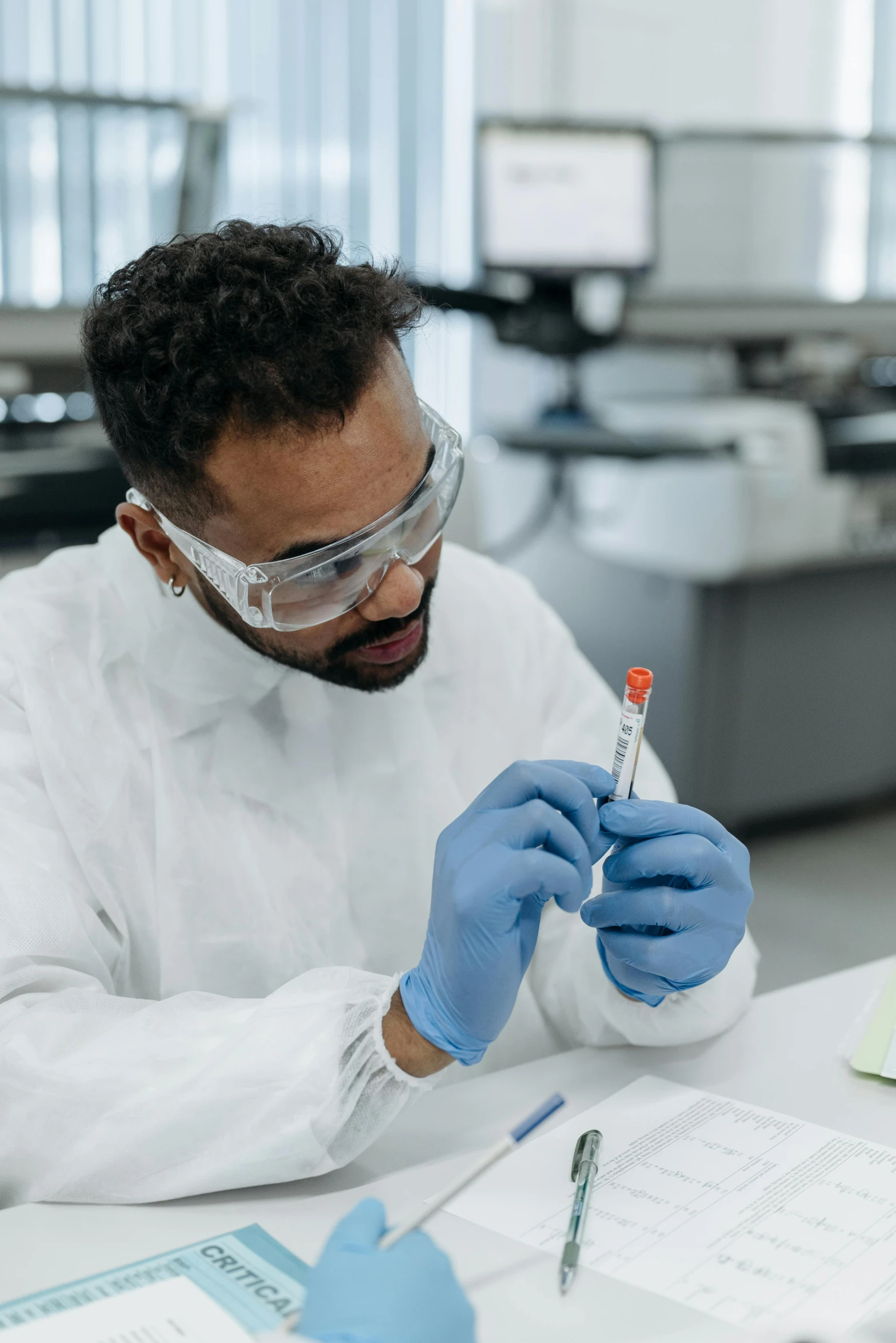 a man in a lab coat and goggles holding a test tube, a picture, pexels, inspect in inventory image, riyahd cassiem, creating a soft, gif