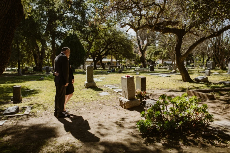 a man standing in the middle of a cemetery, by Elizabeth Durack, unsplash, of a family standing in a park, ignant, 7 0 years old, sydney hanson