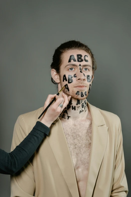 a man with letters painted on his face, by artist, reddit, art & language, promo image, studio photo, abcdefghijklmnopqrstuvwxyz, hozier