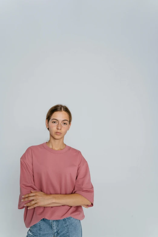a woman standing in front of a white background, a character portrait, pexels contest winner, realism, pink shirt, alessio albi, confident relaxed pose, slightly tanned