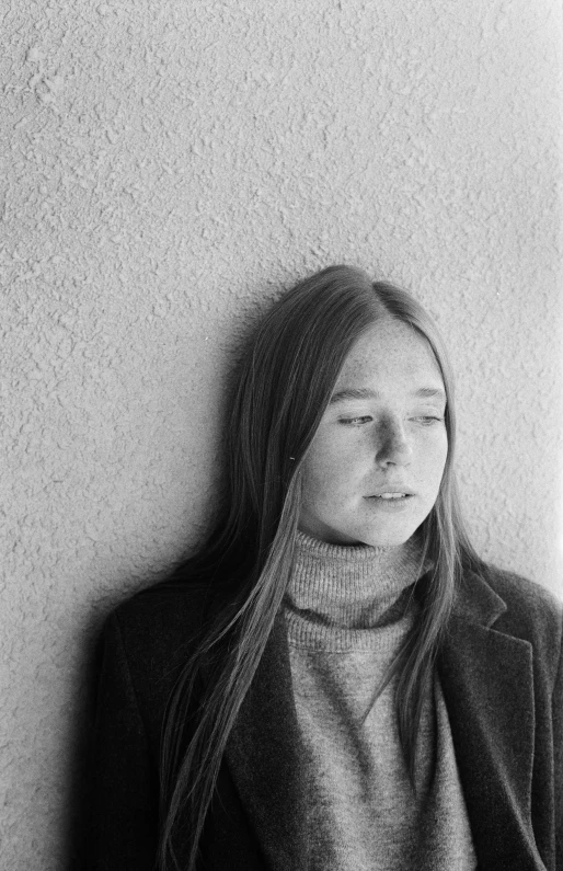 a black and white photo of a woman leaning against a wall, by Grethe Jürgens, aged 13, 1 9 7 0 s, wearing turtleneck, portrait of a young