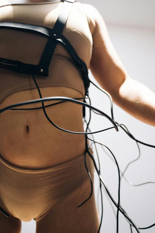 a close up of a body with wires attached to it, inspired by Bruce Nauman, unsplash, sport bra and shirt, earbuds, ignant, brown exoskeleton